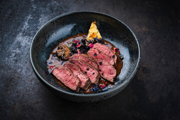 Barbecue dry aged venison steaks - deer entrecote cut english roasted served with grilled mushrooms, fruit berry gravy sauce and panettone herbs served as close-up on a design plate