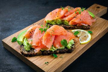 Pumpernickel bread sandwich snack with cured smoked Salmon and fresh avocado served as close-up on...