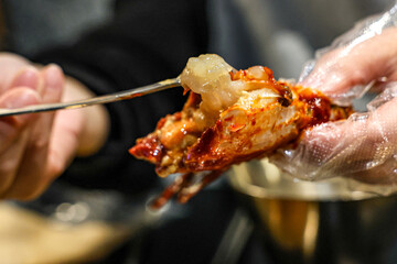 Eating Yangnyeom Gejang – Korean Spicy Marinated Raw Crab Meat with Spoon. Macro shot of Korean Yangnyeom Gejang being eaten, with a spoon scooping translucent raw crab meat.
