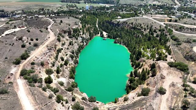 Aerial view of the old Burra copper mine with green lagoon surrounded by rural land on a sunny day