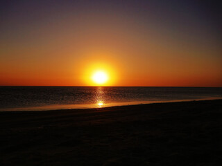 Dull sundown, stuffy air. Sunset over the saltpan lake after a sultry day, dull orange light due to the high humidity