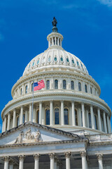 Obraz premium Capitol dome against the blue sky in Washington, D.C. and the U.S. flag in the wind.