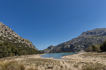 A high altitude dry lake on the Spanish island of Mallorca with green mountains and blue sky