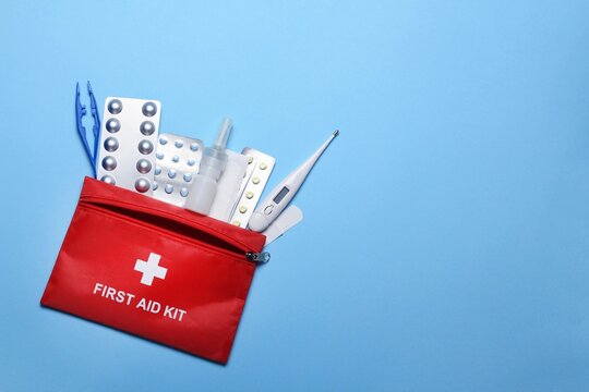Essential first aid kit with medical supplies for home and travel use on a blue background
