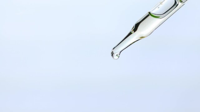 Close-up of clear of Essential oil , Serum droplet falling from a glass dropper on a white background. Perfect for skincare, wellness, or scientific themes etc.,  4K video