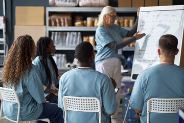 Senior woman leading a training session for diverse group of adult students in classroom while...
