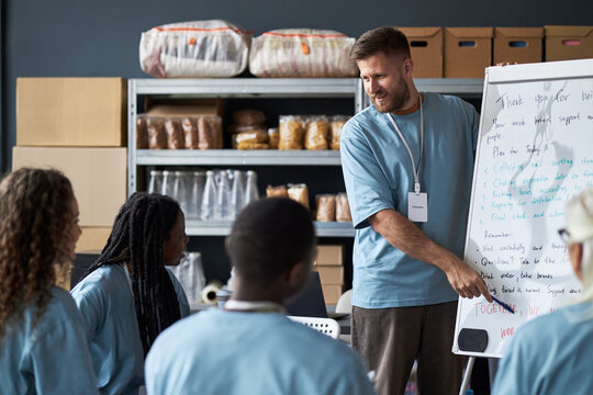 Group of diverse team members engaging in professional discussion while standing around whiteboard in office workspace. Leader writing notes on whiteboard during brainstorming session - Powered by Adobe
