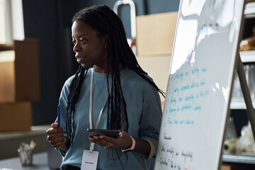 Teaching professional delivering engaging presentation in classroom, holding pen and tablet while...