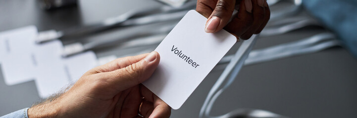 Close-up of hands exchanging volunteer name tag at event, illustrating assistance and involvement....