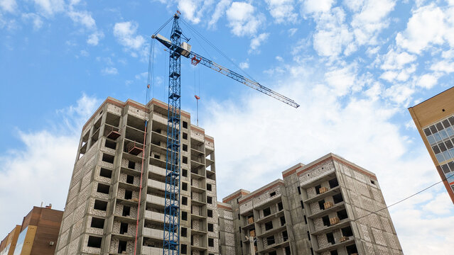 Several high-rise buildings under construction and a large construction crane. Monolithic frame structure with external and internal walls filled with aerated concrete blocks