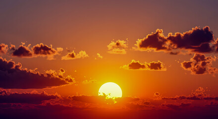 Magnificent sunset with vibrant orange and golden hues illuminating the sky and dramatic clouds forming around the sun.