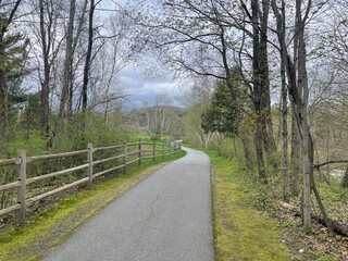 A recreational bike and walking path winds past a split post fence in rural Vermont