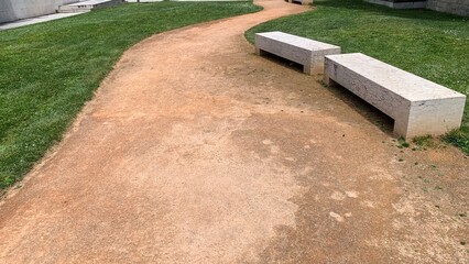 Winding dusty path leading to concrete benches, inviting quiet contemplation during National...