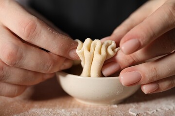 Woman making khinkali on table in kitchen, closeup