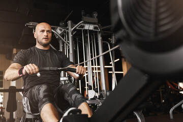 Fototapeta na wymiar Sports, gym and man on rowing machine for health, wellness and body workout in gym. Endurance, exercise and male athlete on ergometer equipment for cardio cross training in fitness center.