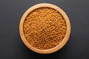 Aromatic mustard seeds in bowl on dark table, top view