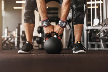 Fototapeta premium Close up of Caucasian man fitness weightlifting with kettlebell for workout exercise training at the gym. Strong male person muscular bodybuilder lifting weight for strength sports intense exercising