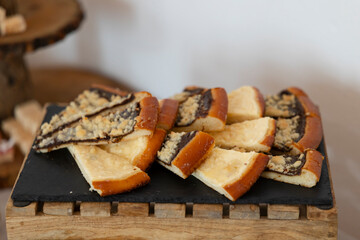 Slices of sweet yeast cake with plum jam and crumble topping lying on black slate plate