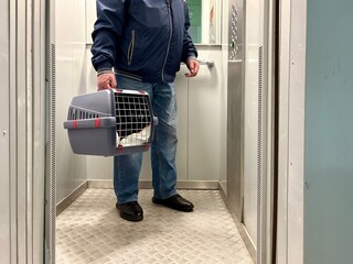 An elderly retired man holds a cat in a carrier. Pet transportation, traveling with a pet. A close friend of an elderly man