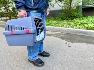 An elderly retired man holds a cat in a carrier. Pet transportation, traveling with a pet. A close friend of an elderly man