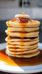 Elevated Golden Pancake Stack with Pouring Maple Syrup and Butter Side Light on a White Plate Delicious Breakfast