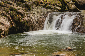 Small waterfall with silky water effect and natural pool in tropical forest, San Rafael, Colombia
