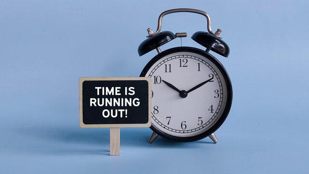 Alarm Clock with Table Sign Displaying "Time Is Running Out!" Representing Urgency, Deadline Pressure, and Last-Minute Alert