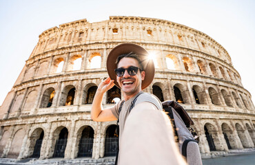 Smiling tourist visiting Coloseum in Rome, Italy - Handsome young man taking selfie with smart...