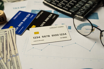 Top view of a finance desk setup including realistic credit cards, hundred-dollar bills, performance charts, and a keyboard. The image evokes themes of financial literacy. Business and Finance