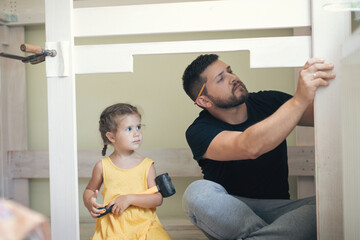 Young man with his daughter assembling furniture at home
