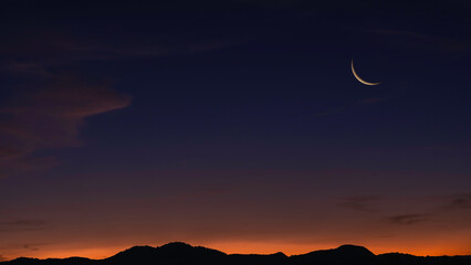Sunset sky over mountain in the evening on twilight with crescent moon on dusk sky, religion of Islamic and free space text Ramadan Kareem, Eid Al Fitr, Eid Al Adha, Eid Mubarak