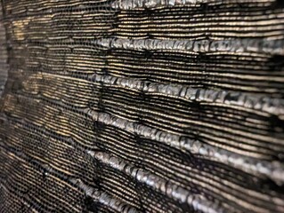 Fototapeta premium Close-up of textured black surface with grooves, abstract detail, black and gold tones, artistic composition