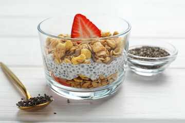 Delicious dessert with chia seeds, yogurt, granola and strawberries in glass on white wooden table, closeup. Superfood
