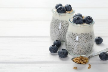 Delicious pudding with chia seeds, yogurt, blueberries and granola on white wooden table, closeup with space for text. Superfood