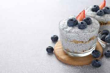 Superfood. Delicious pudding with chia seeds, yogurt, blueberries, granola and strawberry on light grey table, closeup. Space for text