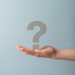hand holds wooden question mark against light blue background, symbolizing curiosity and inquiry