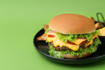 Tasty cheeseburger with sauce and potato wedges on green background, closeup. Space for text