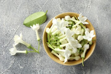 Beautiful jasmine flowers in bowl on grey table, flat lay