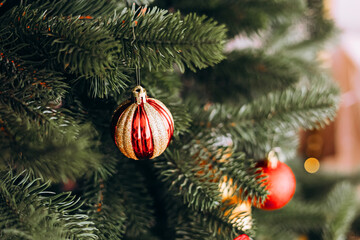 Decorative ornaments hang on a lush green Christmas tree during the holiday season