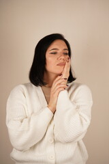 A young woman holds her gum with one hand, her expression showing discomfort. The gesture clearly reflects toothache or pain. The scene conveys a relatable moment of physical unease.