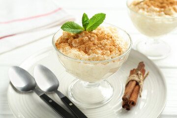 Delicious rice pudding with cinnamon and mint on table, closeup
