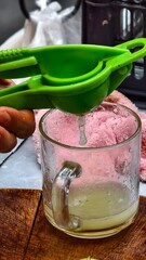 Fresh Citrus Juice Extraction with Green Handheld Juicer in Clear Glass Cup