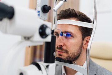 Handsome businessman is undergoing a comprehensive eye examination using advanced diagnostic...