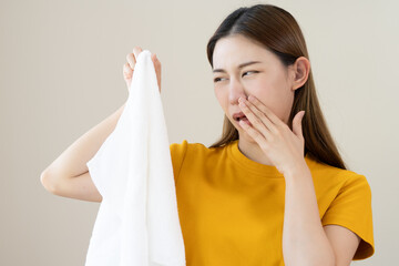 Young people doing laundry smelling for dirty clothes.