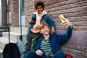 Young boys taking a selfie with a smart phone on a sidewalk in the city after skipping school