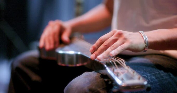 a close up of a guitarist playing slide guitar on their lap