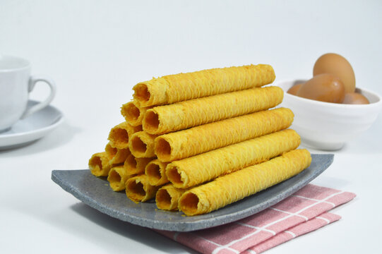 Waffle egg rolls or semprong cake, a traditional Indonesian snack with a unique shape like a layered pipe, served on a gray plate. Selected focus.
