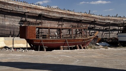 Weathered remains of an early 20th century wooden fishing boat lying abandoned near the shore under...