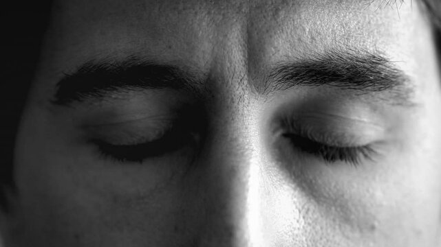 Black and white close-up of a man opening and closing his eyes multiple times, conveying a mindfulness theme. His serene expression emphasizes calmness, inner reflection, meditative state