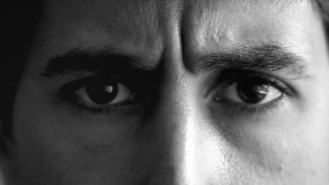 Black and white close-up of a man's eyes with furrowed brows, displaying an intense and serious expression. focus on his gaze suggests deep thought or concentration, strong emotions